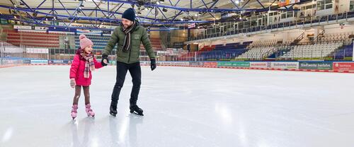 Ein Vater mit seiner Tochter beim Eislaufen in der Eissporthalle Ein Vater mit seiner Tochter beim Eislaufen in der Eissporthalle